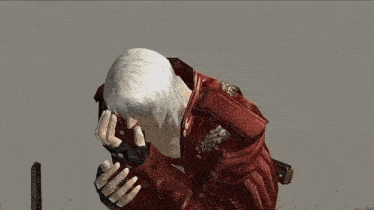 a man in a red jacket is praying with his hands on his face .