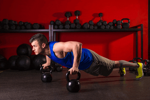 a man in a blue tank top is doing push ups with a kettlebell
