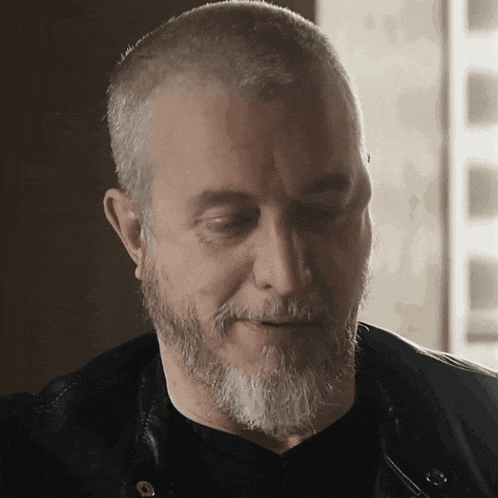 a man with a beard is wearing a leather jacket