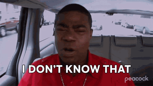 a man in a red shirt is sitting in a car and says " i don 't know that "