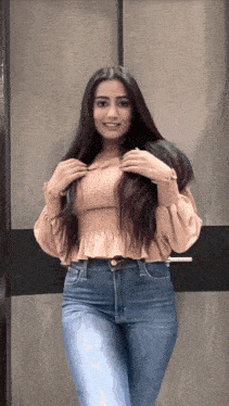 a woman with long dark hair is standing in front of a wooden wall