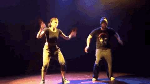 a man and a woman are dancing on a stage with purple lights