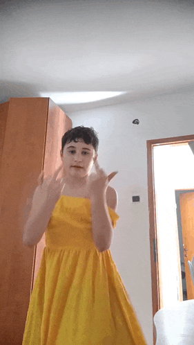 a young girl in a yellow dress giving the middle finger
