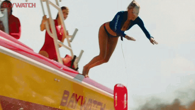 a woman in a bikini is jumping into the water from a boat that says baywatch