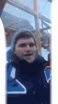 a man wearing a blue jacket with a white triangle on it is smiling