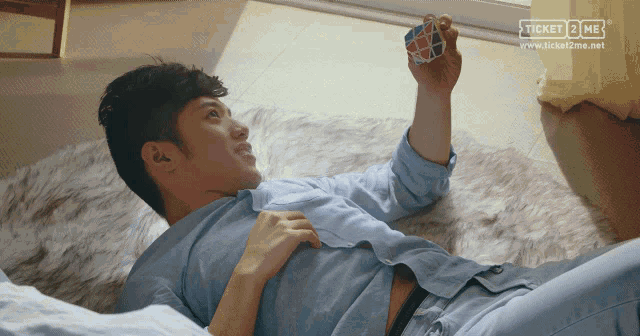 a man laying on the floor with a ticket 2 me logo on the bottom left