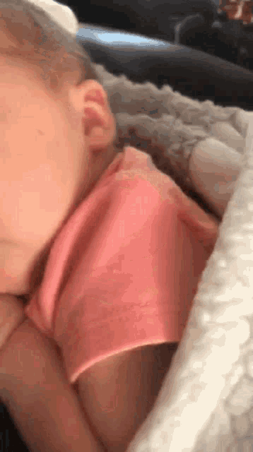 a baby in a pink shirt is laying on a couch .