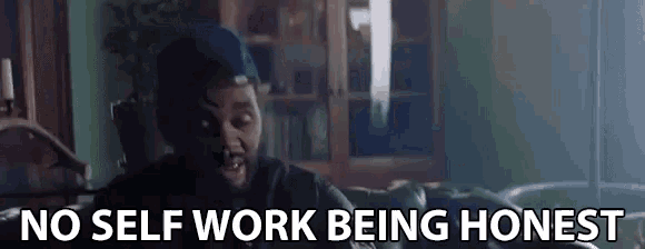 a man with a beard is sitting on a couch and says no self work being honest
