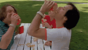 a group of people are sitting at a picnic table eating hamburgers .