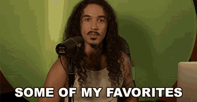 a man with long curly hair is sitting in front of a green screen with the words some of my favorites above him