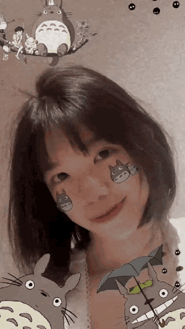 a girl with totoro stickers on her face looks at the camera