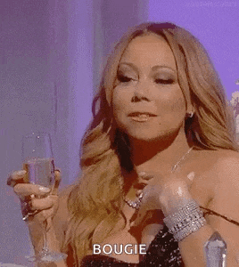 mariah carey is smiling and holding a glass of champagne .