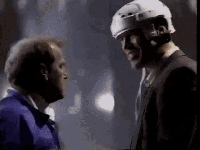 a man wearing a hard hat is talking to another man