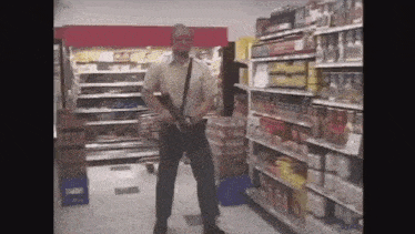 a man is standing in a grocery store with a gun in his hand .