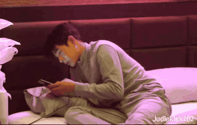 a man with white paint on his face is laying on a bed with judleklek702 written below him
