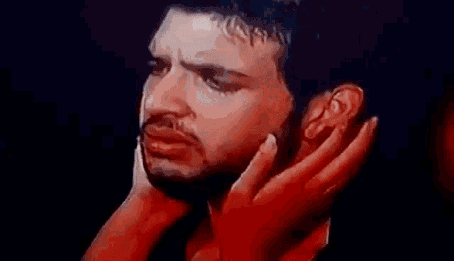 a man with a beard is crying while a woman holds his head .