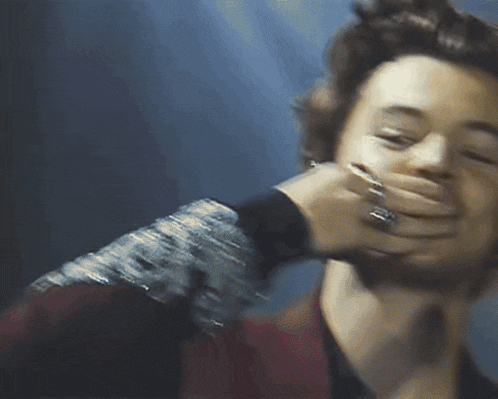 a man with a ring on his finger is covering his mouth with his hand