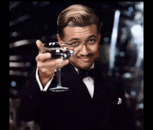 a man in a tuxedo is holding a glass of champagne