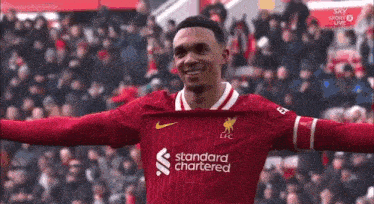 a soccer player is standing on a field with his arms outstretched and smiling .