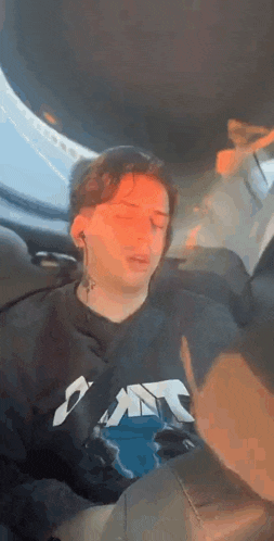 a young man is sleeping in the back seat of a car while wearing headphones .