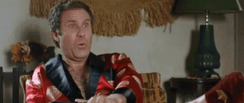 a man in a robe is sitting on a couch with his legs crossed and a lamp in the background .