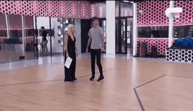 a man and a woman are standing next to each other on a dance floor .