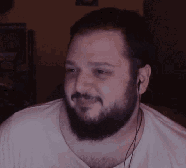 a man with a beard is wearing ear buds and a white shirt