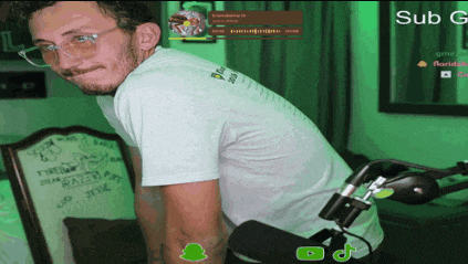 a man wearing glasses and a white shirt is standing in front of a microphone and a green screen that says sub