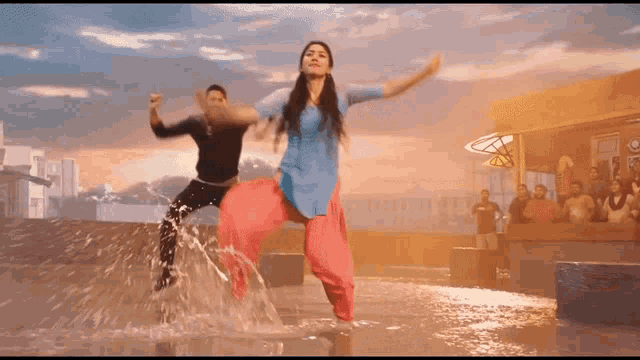 a man and a woman are dancing in the water on a rooftop