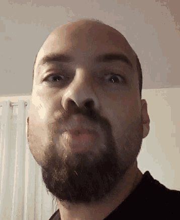 a man with a beard is making a funny face .