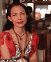 a woman wearing a red top and a butterfly necklace is sitting at a table .