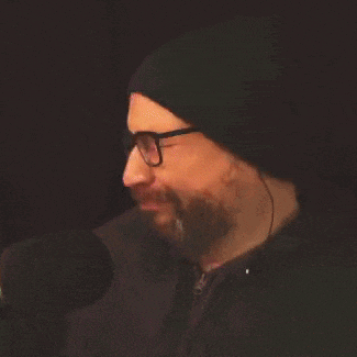 a man with a beard and glasses is wearing a black hat