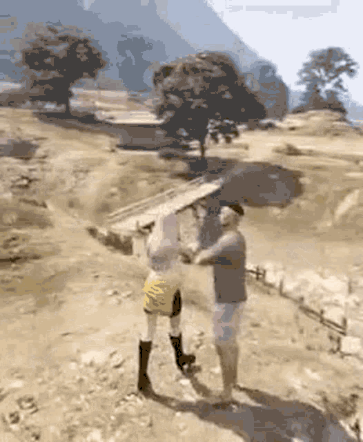 a man and a woman are standing next to each other on a dirt road holding hands .