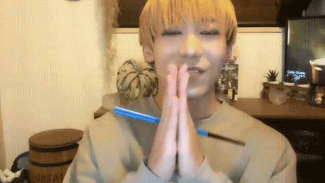 a young man with blonde hair is holding a blue pen in his hands