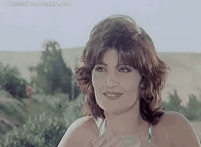a woman is holding a glass of water in her hand and smiling .
