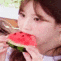 a woman is eating a slice of watermelon with her mouth open .