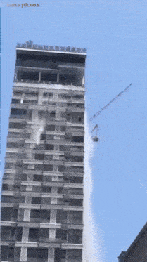 a tall building with a crane attached to it and the word studios on the bottom right