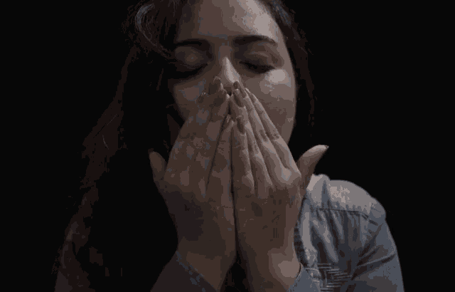 a woman blows a kiss with her hands in front of her face