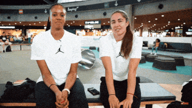 two women sitting on a bench wearing white shirts with the word jordan on them