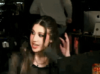 a woman is sitting in front of a computer in a dark room and making a funny face .