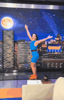a woman in a blue dress is standing on a stage in front of a sign that says come !