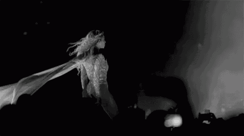 a black and white photo of a woman singing into a microphone on stage .