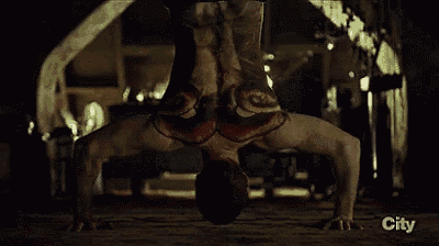 a man is doing a handstand in a dark room with a snake painted on his body .