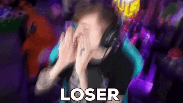 a man wearing headphones is covering his face while sitting in a chair .