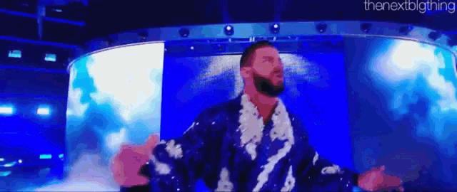a man in a blue robe is standing in front of a large screen .