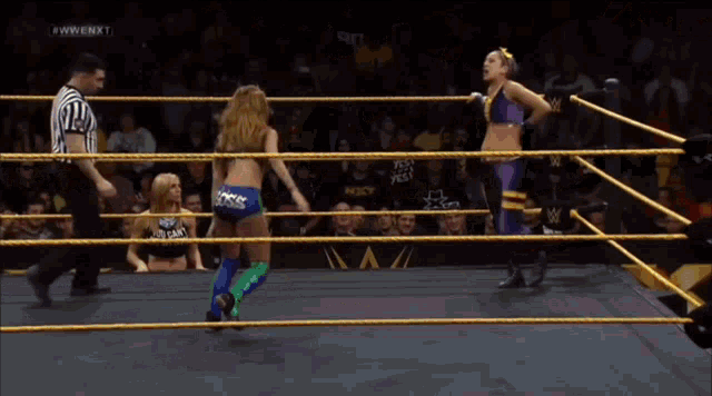 two women are wrestling in a wrestling ring with a w logo on the ring
