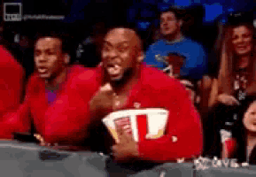 a man in a red sweater is holding a bag of popcorn in his hand .