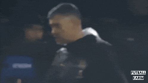 a man in a black jacket with the words futbol karim written on the bottom