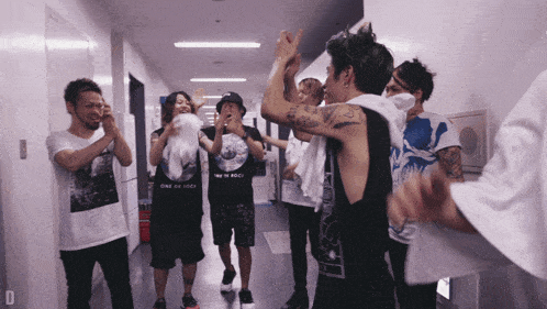 a group of people are standing in a hallway and one of them is wearing a one ok rock shirt
