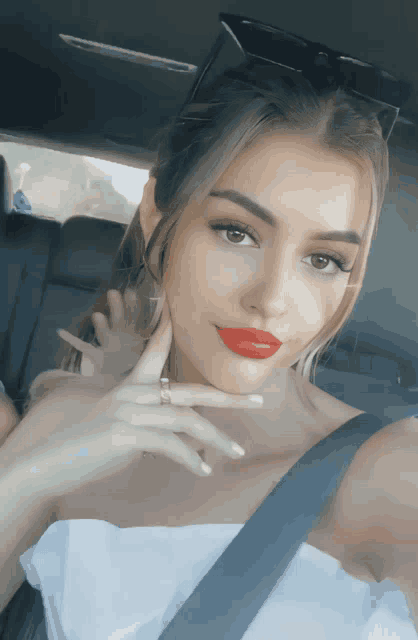 a woman with red lipstick is taking a selfie in the back seat of a car